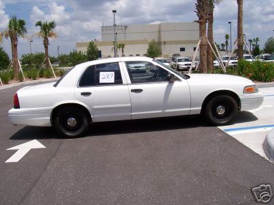 White 2001 Ford Crown Victoria sedan, side view, black wheels, paper with '289' on driver's window