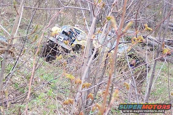Yellow off-road vehicle stuck in brush, partially obscured by branches
