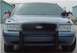 1998 Ford Crown Victoria - Frontal view of a 1998 Ford Crown Victoria police car, equipped with American flags on its side mirrors.