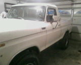 White pickup truck parked inside a garage, showing the front quarter panel and door