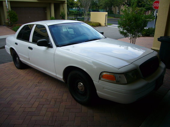 White 2001 Ford Crown Victoria sedan parked on brick pavers, front passenger side visible