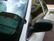 2001 Ford Crown Victoria - A close-up view of a car's side mirror and windshield, with a building reflected in the glass.