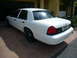 2001 Ford Crown Victoria - A white 2001 Ford Crown Victoria sedan is parked on a brick driveway in front of a garage.