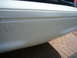2001 Ford Crown Victoria - A close-up of a white car's rear bumper shows faint text, possibly a website, on its surface.