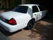 2001 Ford Crown Victoria - A white 2001 Ford Crown Victoria sedan is parked in a driveway, viewed from the rear three-quarter angle.