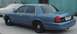 1998 Ford Crown Victoria - A blue 1998 Ford Crown Victoria is parked outdoors next to a covered vehicle.