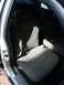 2001 Ford Crown Victoria - The interior of a vehicle shows gray cloth seats and seatbelts, with sunlight casting shadows.