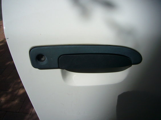 Close-up of a white car door with a black door handle and keyhole