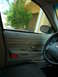 2001 Ford Crown Victoria - The interior of a Ford Crown Victoria shows the door panel, steering wheel, and a glimpse of the outside through the window.