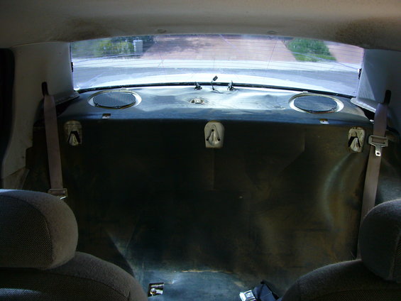 Back seat and trunk area of a car, showing speakers and seatbelts