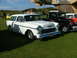 1988 Ford Sport - A classic white 1955 Chevrolet Nomad station wagon is displayed at an outdoor event with other vintage vehicles.