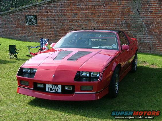 Red sports coupe with hood scoops and a license plate reading D476 UMB