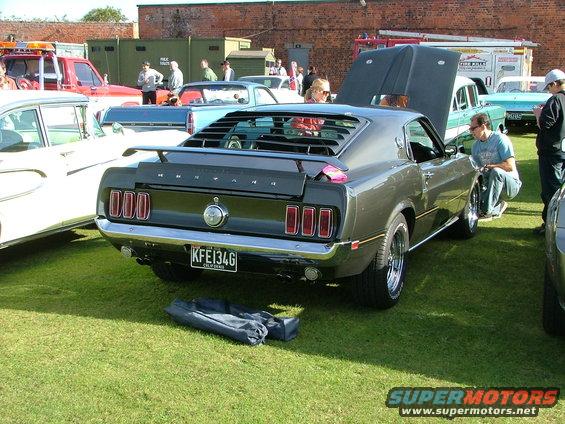 Rear of a dark gray 1969 Ford Mustang with louvers on the back window and a spoiler