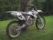 2007 Yamaha YZ450F - A white 2007 Yamaha YZ450F dirt bike is parked next to a tree, showing its side profile with the number 36 visible.