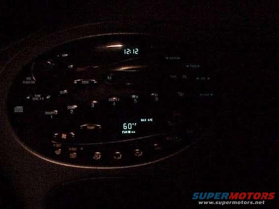 Car dashboard with digital clock showing 12:12 and temperature display showing 60 degrees