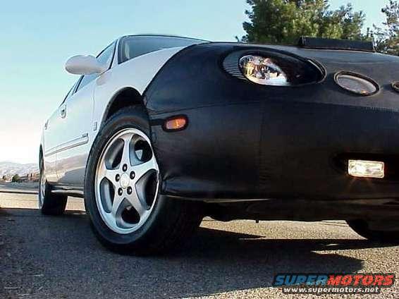 Car with a black bra covering the front end, parked on asphalt