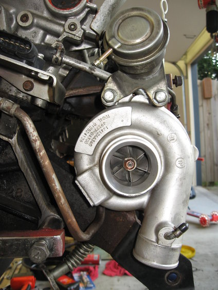 Turbocharger and wastegate assembly on an engine block. Part number 1412AA360 is visible