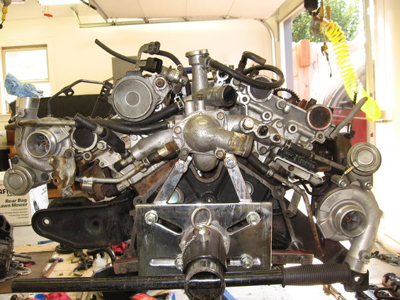 Engine assembly mounted on a stand, showing twin turbochargers and complex plumbing