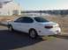 1999 Ford Taurus - Rear view of a white 1999 Ford Taurus sedan parked on a street next to a body of water.