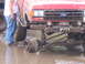 1989 Ford Bronco - A red 1989 Ford Bronco is stuck in mud, its front wheel having detached from the axle.