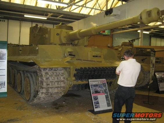 Tan tank with a long barrel and tracks, viewed from the front-right