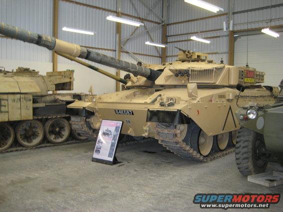 Military tank with license plate 64KG67 and "The Tank Museum" sign. Another tank is visible to the left