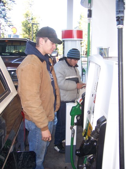 Brown 1980s Ford Bronco side view at gas station with two men