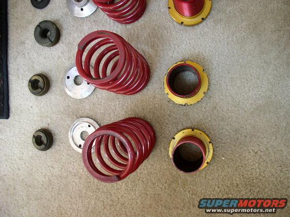 Red suspension springs and yellow/red coilover components on carpet