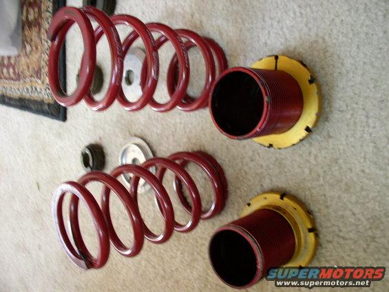 Two red suspension coilover assemblies with adjustable perches
