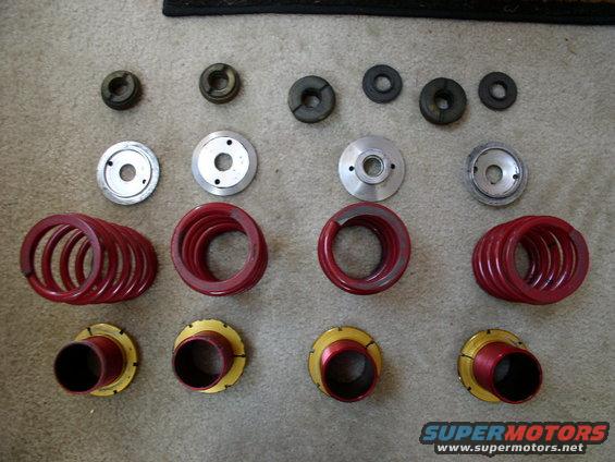 Red suspension springs and assorted metal and rubber components laid out on carpet