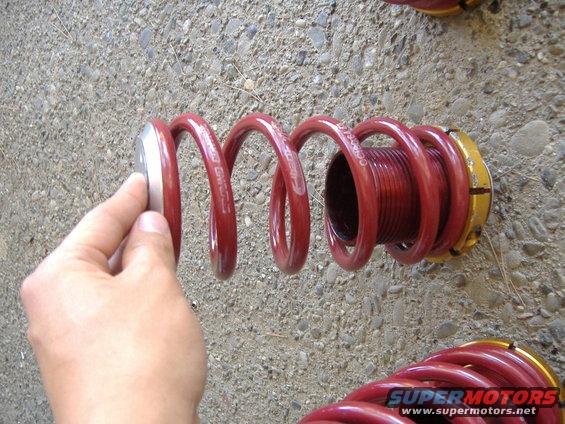 Hand holding silver top of red coilover spring with visible text
