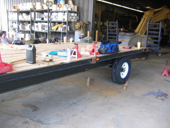 Flatbed trailer with tools, jack stands, and a yellow cup