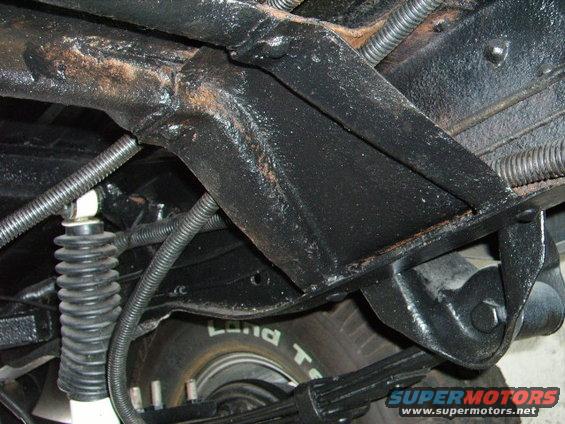 Undercarriage view showing leaf springs, shock absorber, and tire with 'Land T' visible