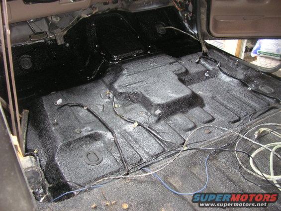 Interior floor of a vehicle after spray-on bedliner application, showing wiring and floor contours