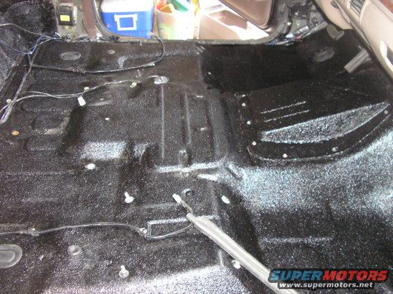 Interior floor of a vehicle with black spray-on bedliner applied. Some wiring is visible