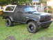 1995 Ford Bronco - Black 1995 Ford Bronco with white removable top parked on grass in front of a house.