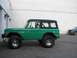 1975 Ford Bronco - Side view of a green 1975 Ford Bronco with a black hardtop, parked outdoors.