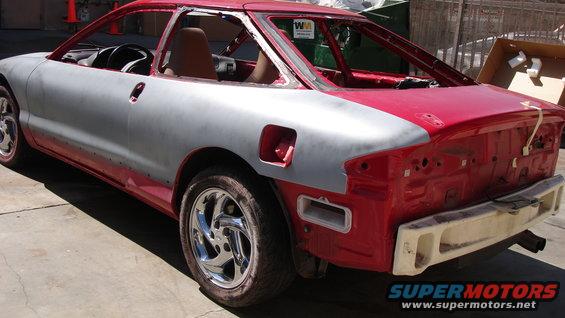 Car body in primer and red paint, missing rear bumper and trunk lid