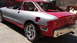 1996 Ford Probe - Car body undergoing repair, showing primer and red paint sections with exposed rear structure.