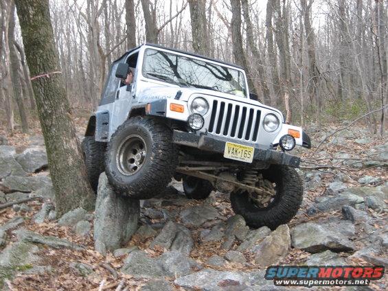 Silver Jeep Wrangler TJ navigating rocky terrain
