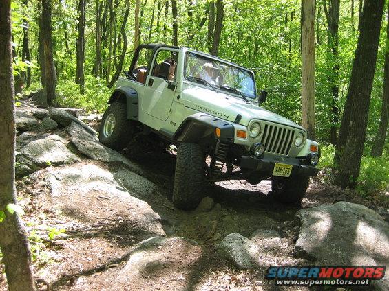 White Jeep Wrangler on rocky trail, front 3/4 view, with 'PARAGON' decal on fender
