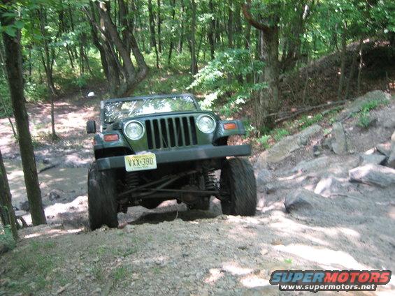 Green Jeep Wrangler on rocky trail, front view