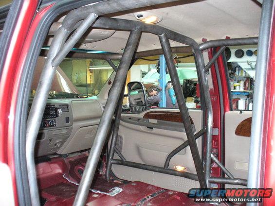Interior of a red truck with a custom roll cage installed. Dashboard and door panels are visible