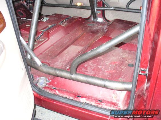 Red vehicle interior with roll cage and exposed floor panels