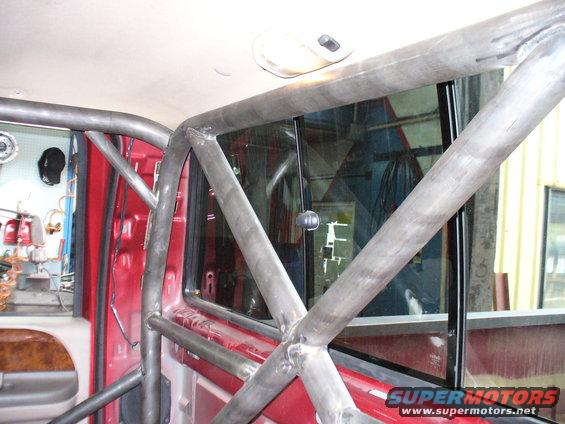 Red interior with a metal roll cage, viewed from the passenger side