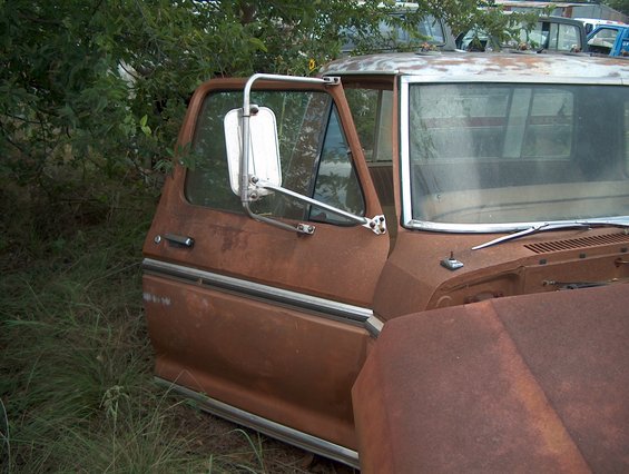 Rusty brown 1979 Ford Bronco cab, driver's side door open, side view