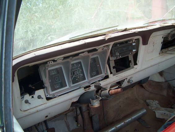 Dashboard of an old truck with gauges and radio removed. Steering column is bare
