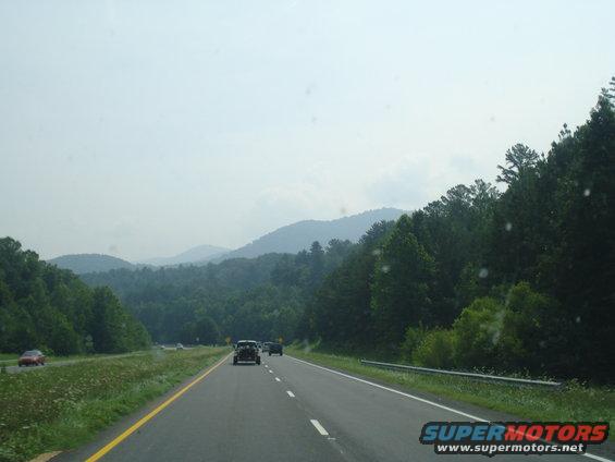 Cars on a highway with mountains and trees in the background