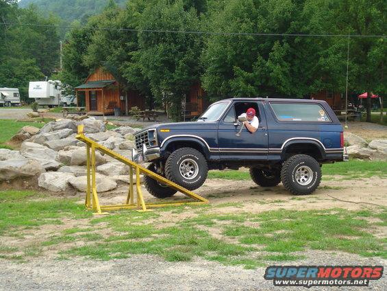 Blue 1980s Ford Bronco driving over rocks on an obstacle course