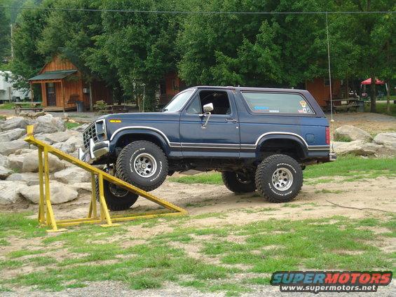 Blue Ford Bronco on a yellow ramp, front tires elevated